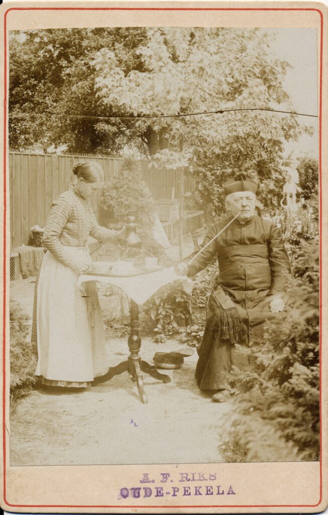 Bekijk de foto's 1 van A.F. Riks: pastoor met lange pijp in de tuin, Oude-Pekela ca. 1893